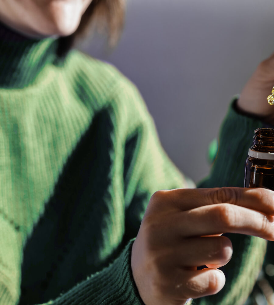 Woman holding a dropper of sublingual cbd cannabis hemp oil - Alternative medical treatment